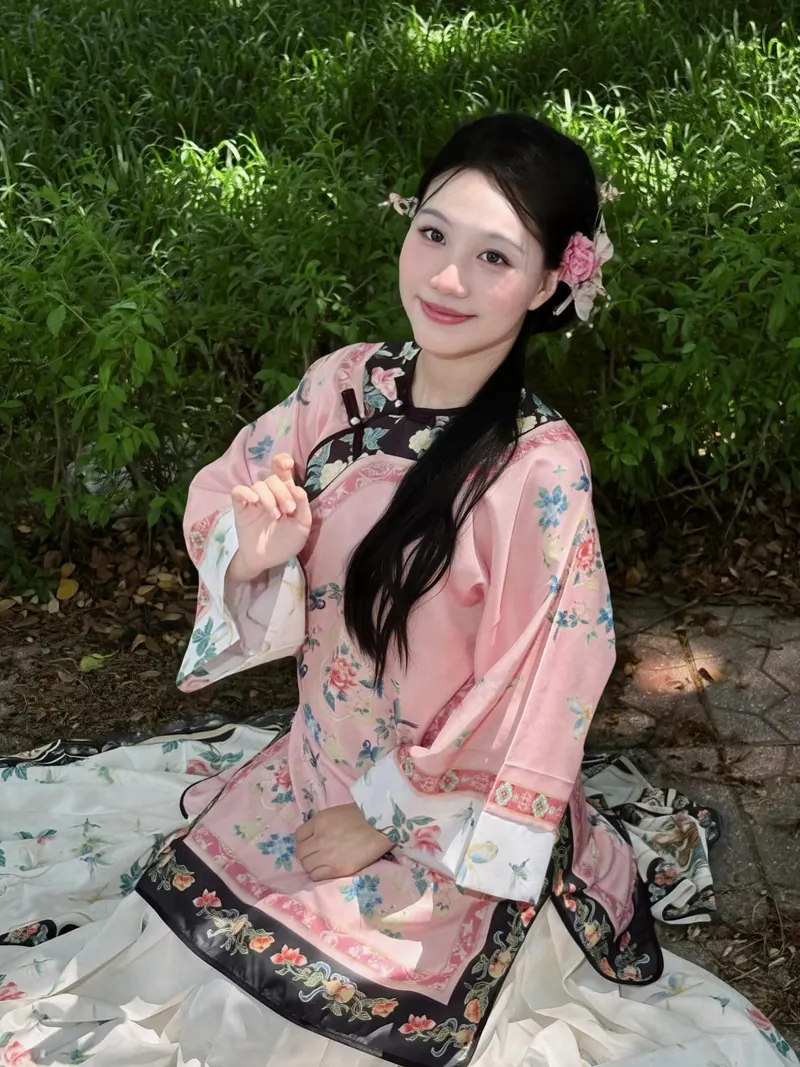 Look 02: a blush brocade robe trimmed in black over an ivory printed skirt, a flower pinned in her hair.
